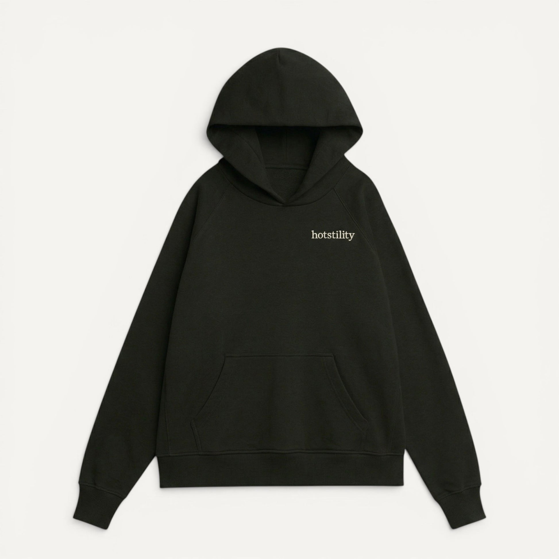 front view of black oversized organic french terry hoodie with "hotstility" embroidered text on chest, relaxed fit with structured silhouette